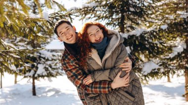 Mutlu evli çift kış parkında sarılıyor. Gençler izin günlerinde kış parkında bir öğleden sonra yürüyüşü yaptılar. Yüksek kalite fotoğraf