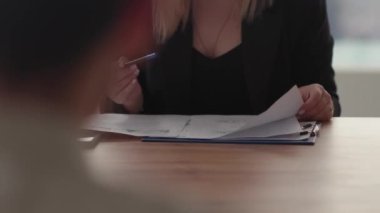 Dosyayı belgelerle inceleyen bir kadının görüntüsü. İş kadını, bir iş toplantısı sırasında ortaklarına şirketin mali durumunu gösteriyor. Yüksek kalite 4k görüntü