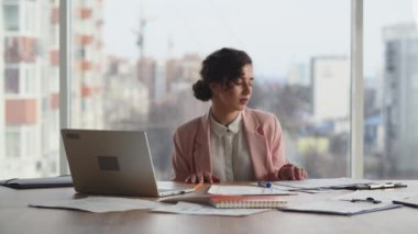 Bir işadamı büyük bir pencerenin önünde ofisinde oturuyor ve şirketlerin mali beyannamelerini sıralıyor. Ofisindeki bir masada oturan bir iş kadını çok sayıda iş kadını gördüğünde iç çeker.