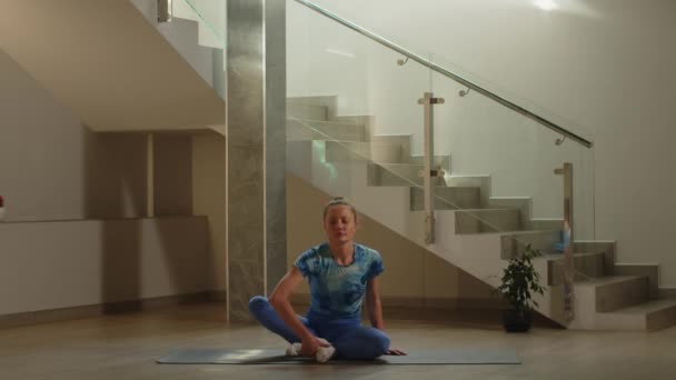 Una Mujer Con Leggins Azules Sienta Una Esterilla Yoga Comienza — Vídeos de Stock