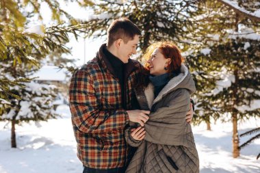 Mutlu yeni evliler kış ormanının ortasında kucaklaşır. Gençler bir randevu sırasında karlı ormanda yürürler. Yüksek kalite fotoğraf