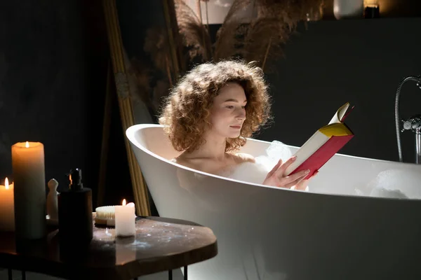 Schöne Frau Liest Ein Buch Während Sie Ein Bad Nimmt — Stockfoto
