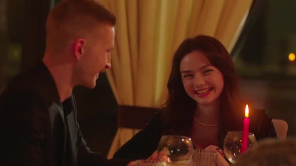 两个年轻人拿着眼镜坐在一张桌子旁 谈论着什么 一个年轻人在餐馆吃饭时和他的女朋友聊得很愉快 高质量的4K镜头 — 图库视频影像