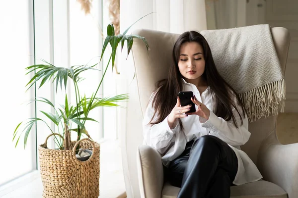 Una Giovane Bruna Attraente Utilizza Uno Smartphone Mentre Seduta Una — Foto Stock