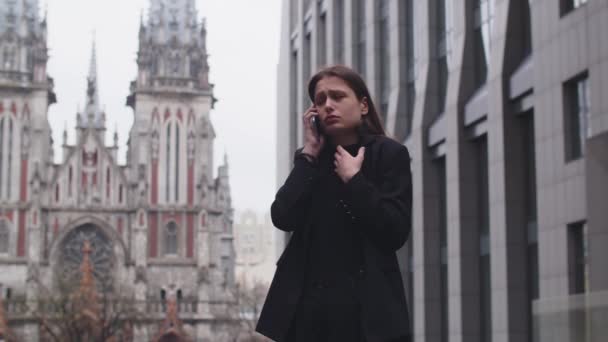 Upprörd Ung Kvinna Pratar Telefon Och Gester Gatan Nära Kyrkan — Stockvideo