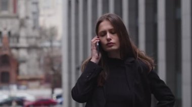 Uzun saçlı esmer bir kadın sokağın ortasında duruyor ve telefonda bir şey konuşuyor. Genç bir iş kadını iş ortaklarıyla telefonda bir görüşme ayarlar. Yüksek kalite 4k