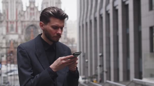 젊은이 길에서 주기적으로 보면서 전화로 무엇인가를타자 비즈니스 슈트를 남자는 자신의 — 비디오