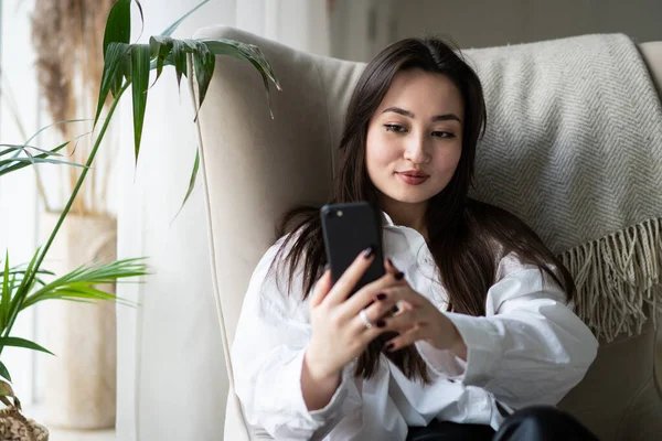 Leende Kvinna Sitter Stol Och Håller Telefon Framför Sig Vacker — Stockfoto