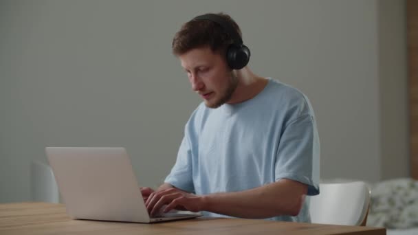 Młody Mężczyzna Niebieskiej Koszulce Pisze Klawiaturze Laptopa Siedząc Przy Stole — Wideo stockowe