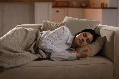 Beyaz gömlekli genç bir bayan oturma odasındaki kanepede uyuyor. İşte yorucu bir günün ardından kanepede uyuyan beyaz gömlekli genç bir kadının fotoğrafı. Yüksek kalite fotoğraf