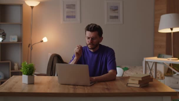 Homem Uma Camiseta Roxa Senta Uma Mesa Seu Quarto Trabalha — Vídeo de Stock