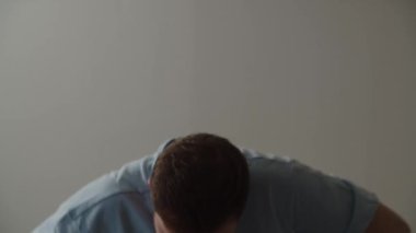 Uyanmış genç adam yatağa oturur ve gözlerini ovuşturur. Uzun bir uykudan sonra sabah uyanan genç bir adamın görüntüsü. Yüksek kalite 4k görüntü