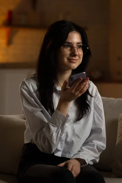 Leende Ung Kvinna Som Sitter Soffan Och Håller Telefon Handen — Stockfoto