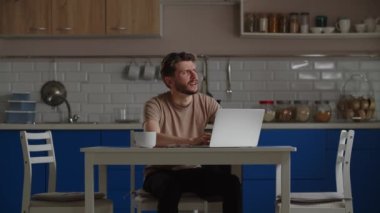 Dairesinde mutfaktayken uzaktan kumandalı bir bilgisayarla çalışan bir serbest çalışan. Laptop klavyesinde yazı yazan genç bir adamın görüntüsü. Yüksek kalite 4k görüntü