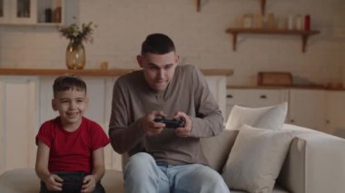 Genç bir baba oğluyla kanepede oturur ve onunla dikkatlice oyun konsolu oynar. Bir adam, bir video oyununda oğluna kaybetti diye üzülür. Yüksek kalite 4k görüntü