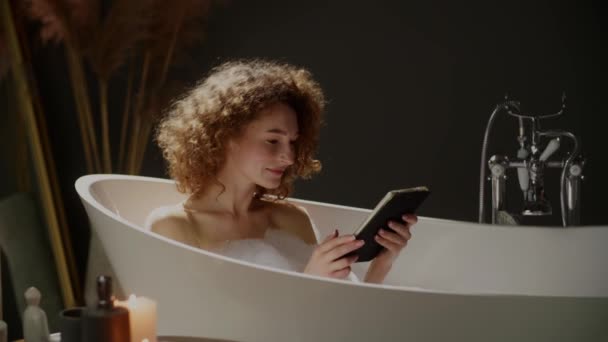 Kędzierzawa Kobieta Stosująca Tabletki Cyfrowe Podczas Kąpieli Uśmiechnięta Dziewczyna Gadżetem — Wideo stockowe