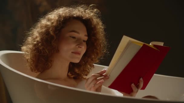 Σγουρή Γυναίκα Που Διαβάζει Ένα Βιβλίο Ενώ Κάνει Μπάνιο Αφρό — Αρχείο Βίντεο