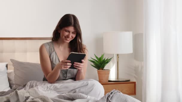 Una Joven Morena Usa Una Tableta Digital Mientras Está Sentada — Vídeos de Stock