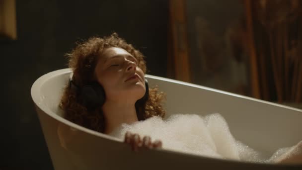Ελκυστική Γυναίκα Σγουρά Μαλλιά Χαλαρώνει Στο Μπάνιο Και Ακούει Μουσική — Αρχείο Βίντεο
