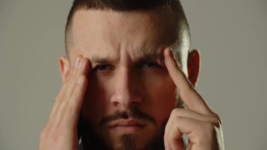 Sakallı adam migren krizi geçiriyor. Esmer adam gri arka planda izole edilmiş baş ağrısından muzdarip. Yüksek kalite 4k görüntü