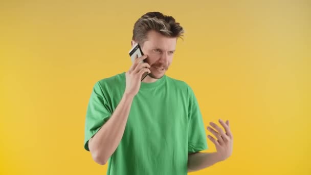 Emocjonalny Młodzieniec Rozmawiający Przez Telefon Odizolowany Żółtym Tle Nieprzyjemna Rozmowa — Wideo stockowe