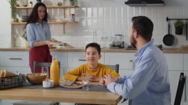 Bir baba mutfakta kahvaltı sırasında oğluyla iletişim kurar. Esmer bir kadın oğlunun ve kocasının önüne tabak tabak kahvaltı koyar. Arkadaş canlısı bir aile mutfakta kahvaltı eder.
