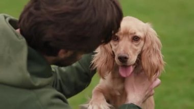 Kapüşonlu esmer adam köpeğini okşuyor. Koyu saçlı adam köpek yavrusuyla dışarıda vakit geçiriyor. Yüksek kalite 4k görüntü