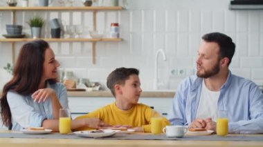 Bir çocuk okuldaki gününün nasıl geçtiğini ailesine anlatır. Ebeveynler masaya oturur ve oğullarına sarılırlar. Yüksek kalite 4k görüntü