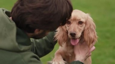 Kapüşonlu esmer adam köpeğini okşuyor. Koyu saçlı adam köpek yavrusuyla dışarıda vakit geçiriyor. Yüksek kalite 4k görüntü