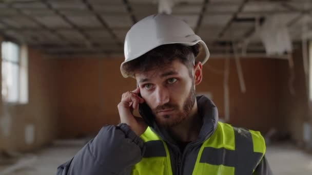 Seorang Pria Dengan Helm Konstruksi Putih Berdiri Tengah Tengah Lokasi — Stok Video