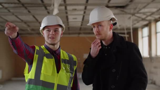Два Человека Белых Шлемах Осматривают Стройплощадку Обсуждают Мастер Строитель Обсуждают — стоковое видео