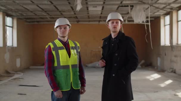 建物検査官は工事現場を確認した後 建物と握手をする 建設ヘルメットの2人の男性が建設現場を見て回る 高品質4K映像 — ストック動画