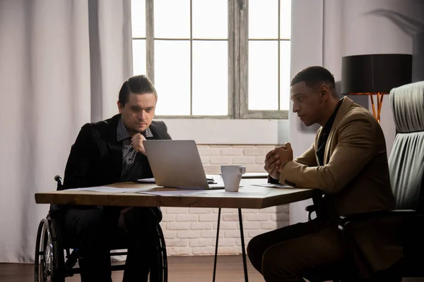 正式なスーツを着た2人の男性がオフィスに座ってノートパソコンの画面を見ています ビジネスパートナーはテーブルに座り ノートパソコンで会社のレポートを勉強します 高品質の写真 — ストック写真