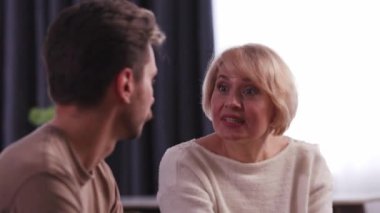 Annem yetişkin oğlunu azarlıyor ve kanepeden kalkıp gidiyor. Bir adam kanepeye oturur ve annesi ona bağırdıktan sonra bir şey düşünür. Yüksek kalite 4k görüntü