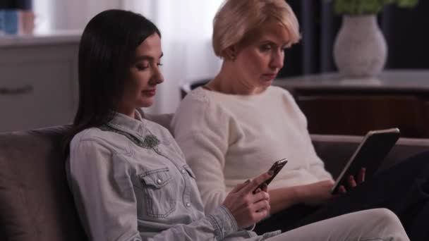 Uma Jovem Morena Está Sentada Sofá Com Telefone Nas Mãos — Vídeo de Stock