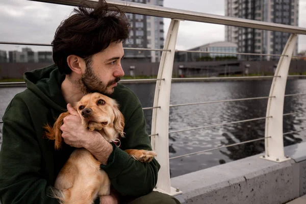 Young Brunette Man Sits Park River Holds Cocker Spaniel His — Stock Photo, Image