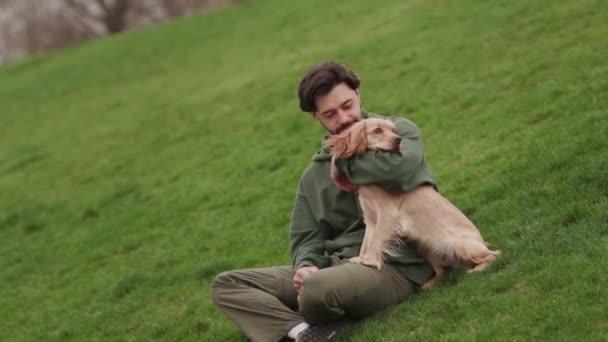 Een Man Zit Een Kleine Groene Heuvel Met Zijn Hond — Stockvideo