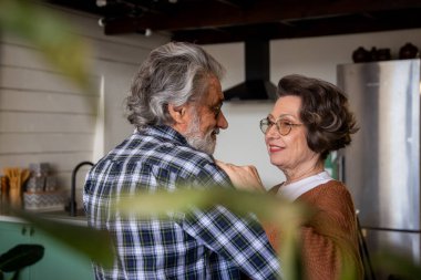 Mutlu yaşlı çiftin seçici odak noktası evde dans etmek ve birbirlerine sevgiyle bakmaktır. Yüksek kalite fotoğraf