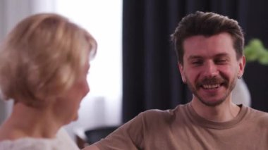 Mutlu genç adam annesiyle konuşuyor ve gülüyor. Orta yaşlı anne ve oğlu birlikte eğleniyor. Anneler günü, aile ilişkisi. Yüksek kalite 4k görüntü