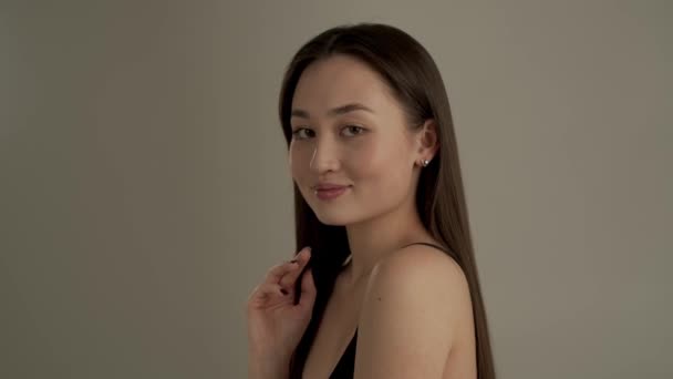 Hermosa Chica Asiática Mirando Cámara Con Sonrisa Tocando Cabello Aislado — Vídeo de stock