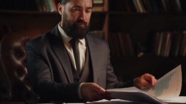 Büyük bir şirketin müdürü ofisinde oturur ve raporlara bakar. Bir erkek işadamı ofisteki bir masaya oturur ve bir belgeye imzasını atar. Yüksek kalite 4k görüntü