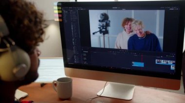 Kulaklık takan adam video prodüksiyonu üzerinde çalışıyor. Video düzenleyici monitöre bakar. Yüksek kalite 4k görüntü