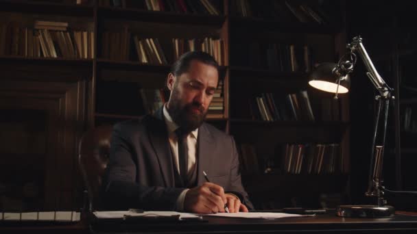 Ένας Άντρας Μαύρο Σακάκι Κάθεται Ένα Τραπέζι Και Μελετά Διάφορα — Αρχείο Βίντεο