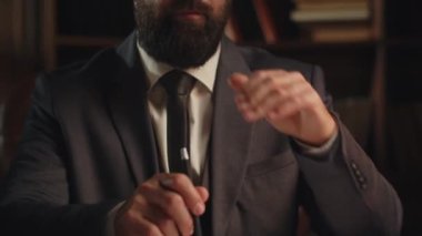 Siyah ceketli sakallı bir adam masaya oturur ve bir şey düşünür. Erkek bir işadamı şirketin finansal akışını nasıl optimize edeceğini düşünüyor. Yüksek kalite 4k görüntü