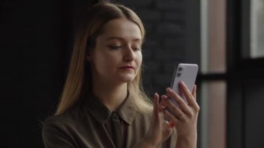 Genç bir kadın hemen akıllı telefon ekranına bağlanıyor. Uzun saçlı sarışın bir kadın, bir haberci aracılığıyla akıllı telefondan arkadaşıyla sohbet ediyor. Yüksek kalite 4k görüntü
