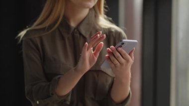 Akıllı telefon ekranında kayan bir kadının görüntüsü. Sarışın kadın akıllı telefondan sosyal medyada arama yapıyor. Yüksek kalite 4k görüntü