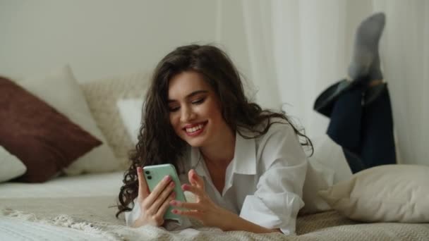 Brunette Κορίτσι Χρησιμοποιώντας Smartphone Της Ενώ Βρίσκεται Στο Κρεβάτι Στην — Αρχείο Βίντεο