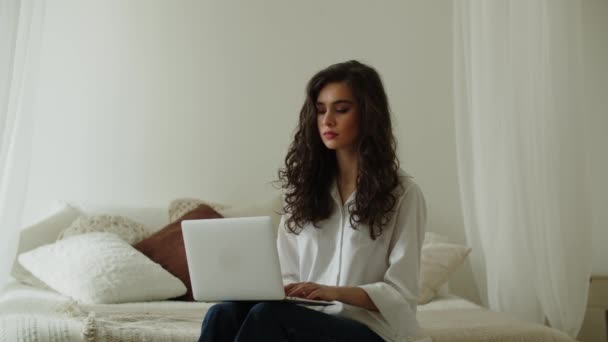Mulher Morena Sorridente Está Sentada Cama Seu Quarto Digitando Laptop — Vídeo de Stock