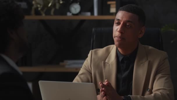 一位身穿棕色夹克的黑人男性商人坐在办公室里与他的员工交流 商业伙伴正在讨论公司发展的新方向 高质量的4K镜头 — 图库视频影像