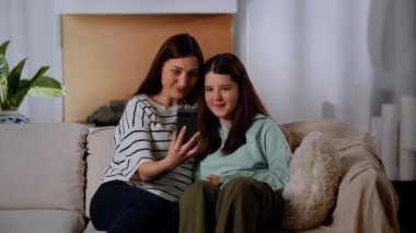 Anne ve kızı kanepede oturuyorlar ve akıllı telefondan biriyle video bağlantısı üzerinden konuşuyorlar. Oturma odasında annesinin yanında oturan küçük bir kız babasıyla iletişim kuruyor.